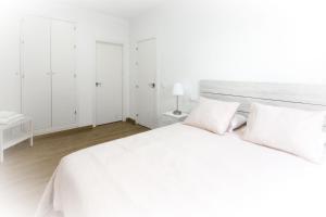 a white bedroom with a large white bed with two pillows at Apartamento San Juan in El Puerto de Santa María