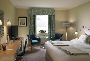 een hotelkamer met een bed, een bureau en stoelen bij The Goodwood Hotel in Chichester