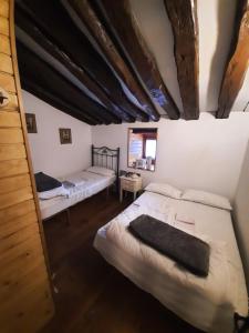 Habitación con 3 camas y techo de madera. en Cabaña Pasiega La Quemada, en San Pedro del Romeral