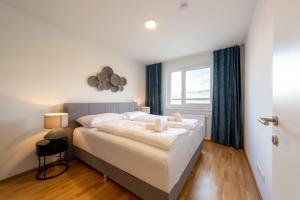 a bedroom with a large white bed with a window at Modernes Stadtapartment mit Terrasse in Vienna