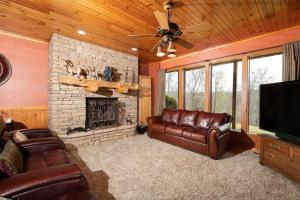 a living room with leather furniture and a stone fireplace at Smoke Rise Lodge · Lake Front, Luxury Cabin, Hot Tub, in Dandridge