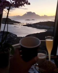 a person holding a glass of beer on a table with a view at Aurora Hut by InukTravel in Nuuk