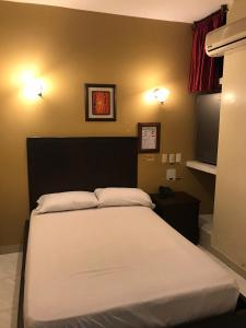 1 dormitorio con 1 cama y 2 luces en la pared en Hotel Pegazus, en Guayaquil