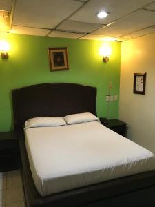 Cama en habitación con pared verde en Hotel Pegazus, en Guayaquil