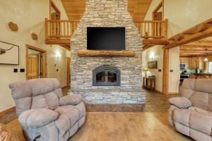 a living room with two chairs and a stone fireplace at Woodland Wonder in Brian Head