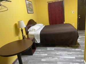 a small bedroom with a bed and a table at Azure Sky Motel in Fort Scott