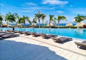 a resort pool with chaise lounge chairs and palm trees at Best Luxury Samaria in Santa Marta