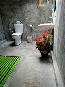 a bathroom with a toilet and a sink and flowers at Moksha eco villa Ella in Ella