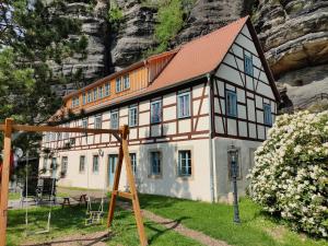 een huis met een rood dak voor een berg bij Ferienwohnungen Felsenkeller Bielatal in Bielatal