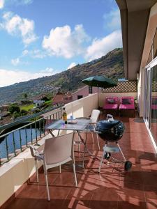 uma varanda com mesa, cadeiras e comodidades para churrascos em Vista Romantica Madeira em Arco da Calheta