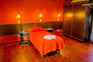 czerwony pokój z łóżkiem z pomarańczowym kocem w obiekcie Hotel Villa Sol w mieście Merlo