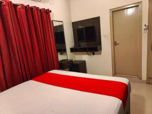 a bedroom with a bed with red curtains and a television at Pristine Inn Manyata in Bangalore