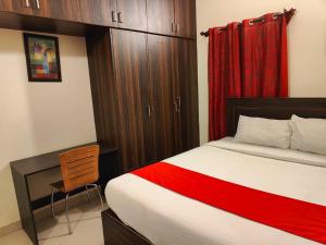a bedroom with a bed and a desk with a red curtain at Pristine Inn Manyata in Bangalore