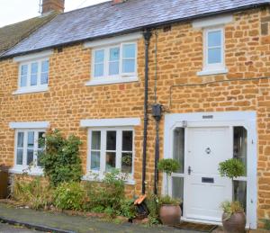 a brick house with a white door and windows at Idyllic Country Cottage near Soho, Oxford & Cotswolds in Banbury