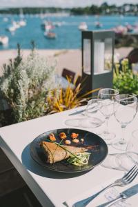 a plate of food on a table with a view of the ocean at Hotel Du Bac in Combrit