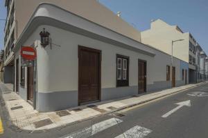 een wit gebouw met bruine deuren op een straat bij Los Adelantados La Hornacina Live Canarias in La Laguna