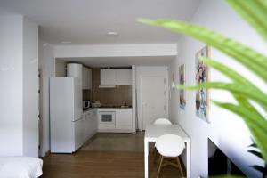 a white kitchen with a table and a refrigerator at Apartamento San Juan in El Puerto de Santa María +3 photos