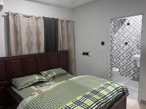 a bedroom with a bed and a bathroom with a shower at T-Roys Apartments in Accra