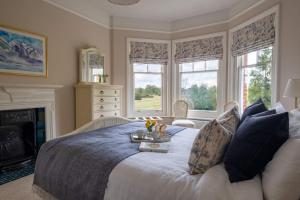 a bedroom with a bed with a fireplace and windows at Surrey Lodge in Brockenhurst