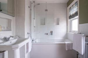 a white bathroom with a tub and a sink at Surrey Lodge in Brockenhurst +53 photos