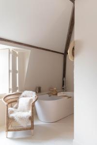 a bath tub in a room with a chair and a bath tub at Het sfeerhuis aan zee in Vlissingen