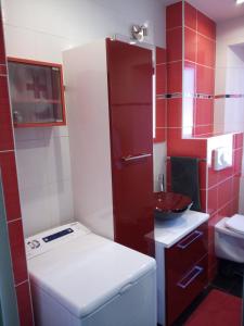- une petite salle de bains rouge et blanche avec lavabo dans l'établissement Au Bercail, à Gérardmer