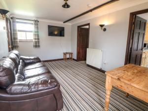 un soggiorno con divano in pelle e tavolo in legno di Monsal Cottage a Bakewell