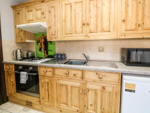 una cucina con armadi in legno e lavandino di Monsal Cottage a Bakewell