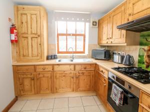 a kitchen with wooden cabinets and a sink and a stove at Haddon Cottage in Bakewell