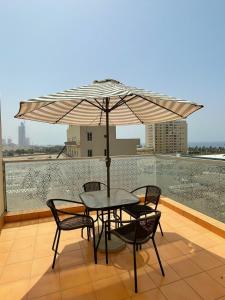 a table and chairs with an umbrella on a balcony at Sarwat Park Hotel Jeddah in Jeddah