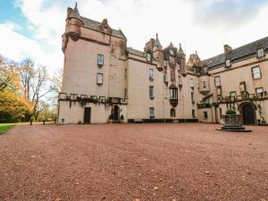 an old castle with a dirt courtyard in front of it at The Preston Tower Apartment - Fyvie Castle in Turriff