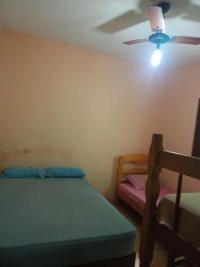 una camera da letto con un letto e un ventilatore a soffitto di Casa com piscina em Mongaguá a Mongaguá