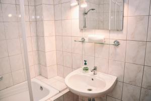 La salle de bains blanche est pourvue d'un lavabo et d'une douche. dans l'établissement Pension s'Platzl Stuhleck, à Spital am Semmering