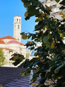 a building with a clock tower in front of a tree at Modern & Rustic Apartment - City Center. in Pristina