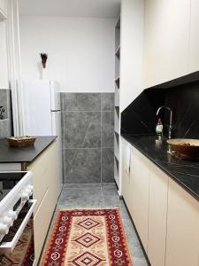 a kitchen with white cabinets and a red rug at Modern & Rustic Apartment - City Center. in Pristina