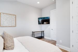 a white bedroom with a bed and a tv at Sojourners Haven - 2 Mi To Downtown & Broadway in Nashville