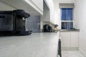 a kitchen with a white floor and a large window at Cosy & Comfortable - Heart of Hove - Beach Getaway in Brighton & Hove
