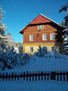 ein Haus mit rotem Dach im Schnee in der Unterkunft Pension Familia in Harrachov