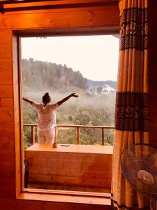 kobieta stojąca na balkonie patrząca przez okno w obiekcie Green Nature Paradise Ella w mieście Ella