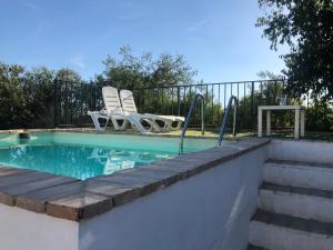 a swimming pool with two lawn chairs next to a fence at Casa del Almezo in Almodóvar del Río