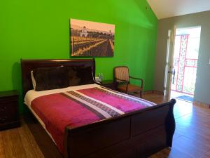 Posada Del Valle في فالي دي جوادالوبي: غرفة نوم بجدران خضراء وسرير في غرفة