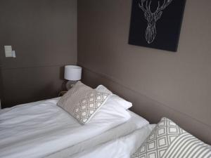 Una cama con sábanas blancas y almohadas en un dormitorio en Ellin Pooli 3, en Sastamala