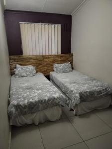 dwa łóżka siedzące obok siebie w pokoju w obiekcie Lotus Guest House 1 w mieście Durban