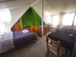 a bedroom with a bed and a table and a green wall at Cinerama Hostel in San Carlos de Bariloche