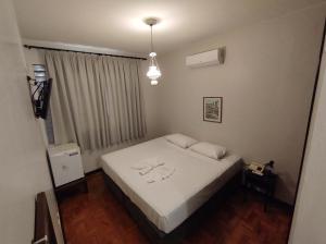 um quarto com uma cama branca e uma janela em Hotel Itarare em Itararé