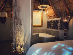 a bedroom with a tub and a bed in a room at Little Eden Guest Lodge in Vanderbijlpark