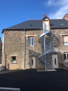 a building with a spiral staircase on the side of it at Résidence Merlin Appartement Arthur in Saint-Malon-sur-Mel