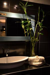 a bathroom with a sink and a vase with a plant at Little Eden Guest Lodge in Vanderbijlpark