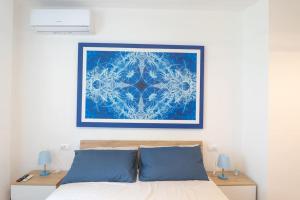 ein Gemälde über einem Bett mit blauen Kissen in der Unterkunft Appartamento incantevole fronte mare in Villa Rosa