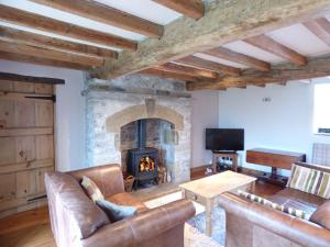 a living room with a fireplace and leather furniture at Hall End Barn in Buxton